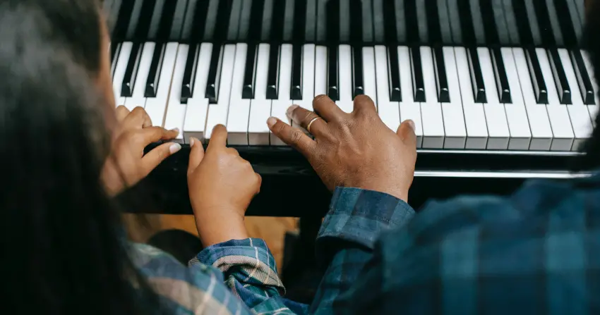 En vuxen och ett barn spelar piano