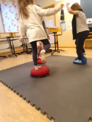 Flicka balanserar på boll i klassrum